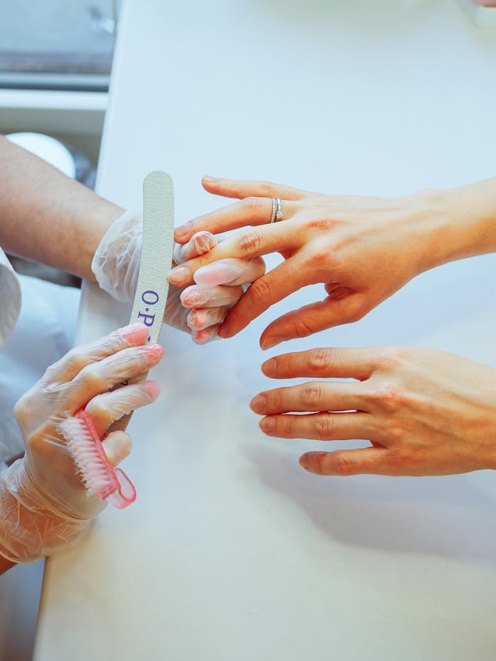 Close-up of a manicurist filing nails with precision and care in a salon setting.