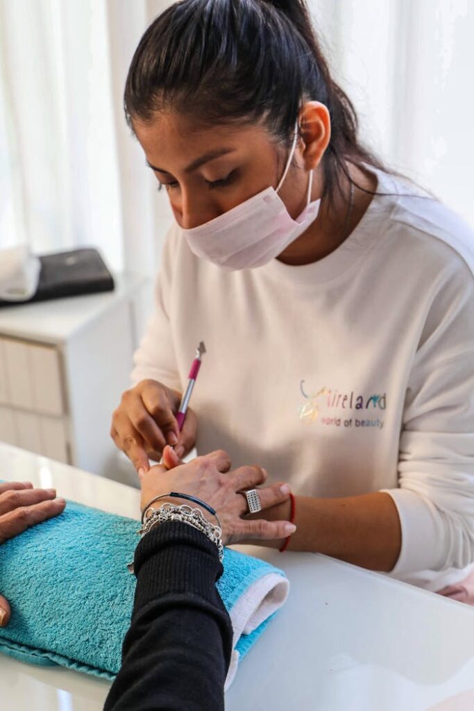 A nail technician carefully applies nail polish to a client's hand in a salon setting.