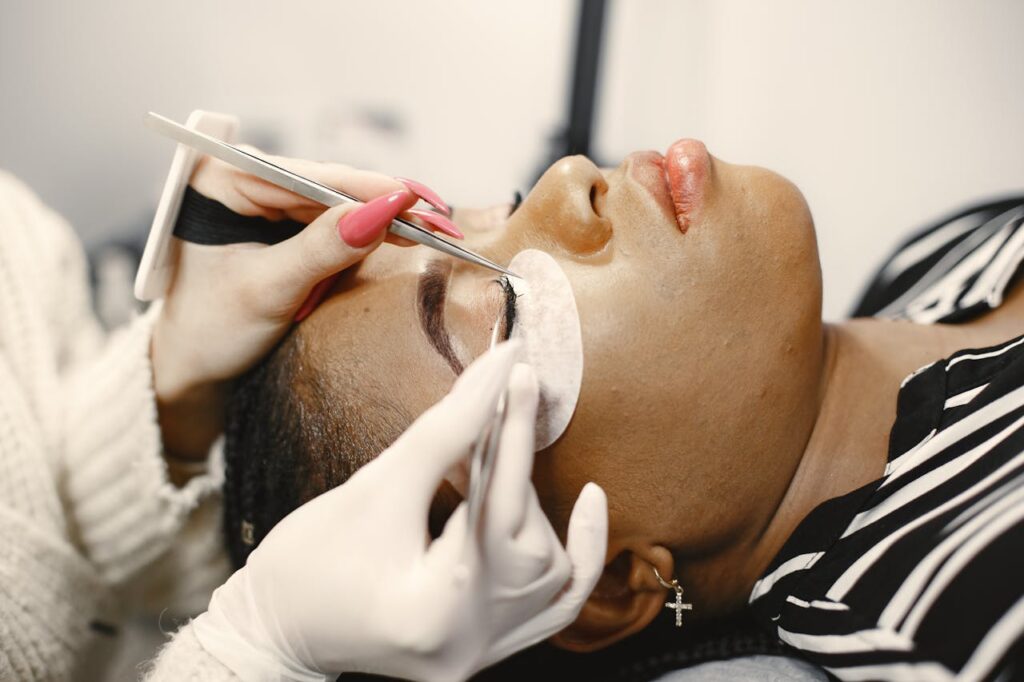 A close-up view of a woman receiving an eyelash extension treatment in a beauty salon.